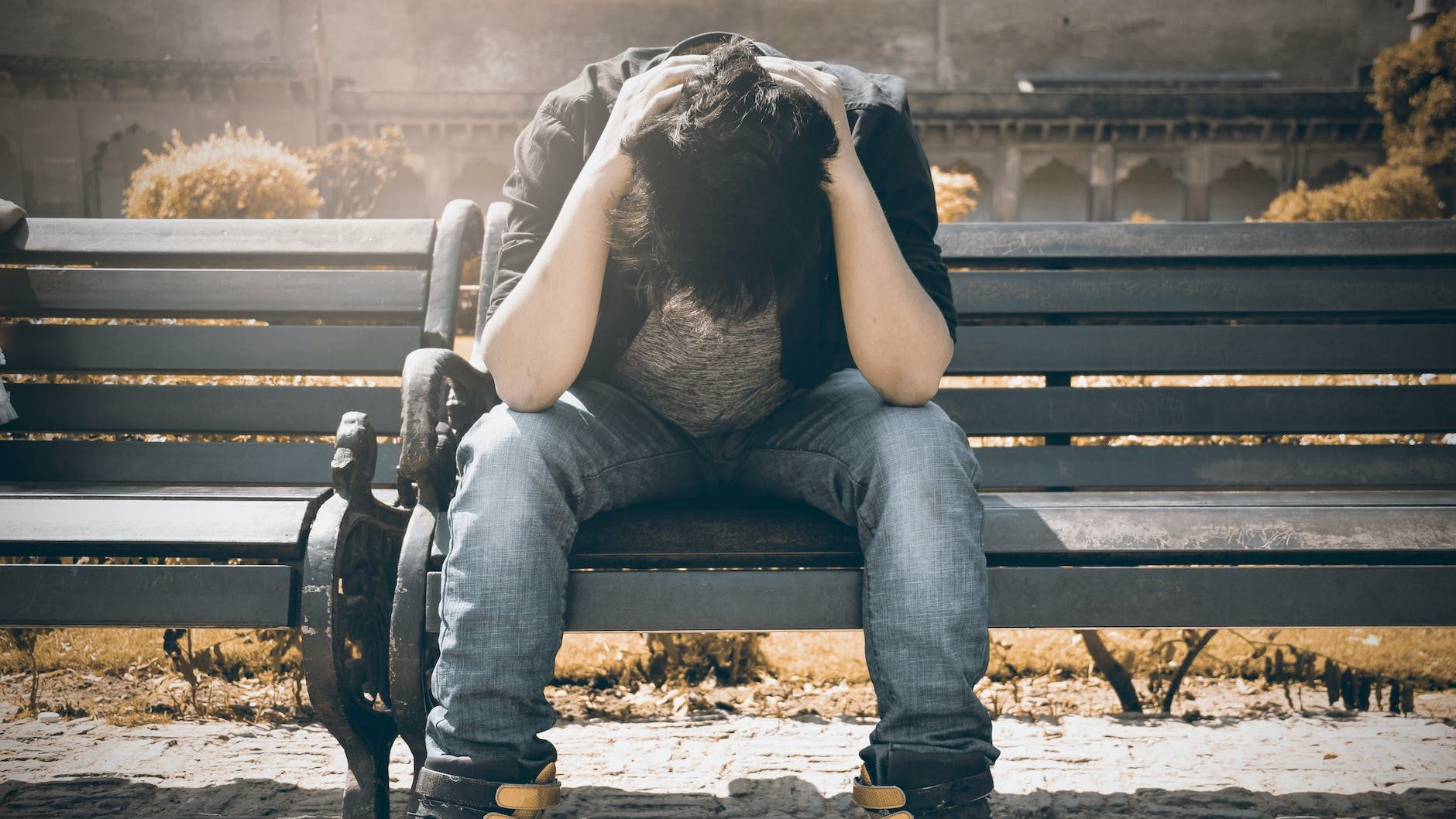 A person sits alone, contemplating their emotions while coping with grief. JENNIFER ADAIR, LPC. ONESTA THERAPY CO.