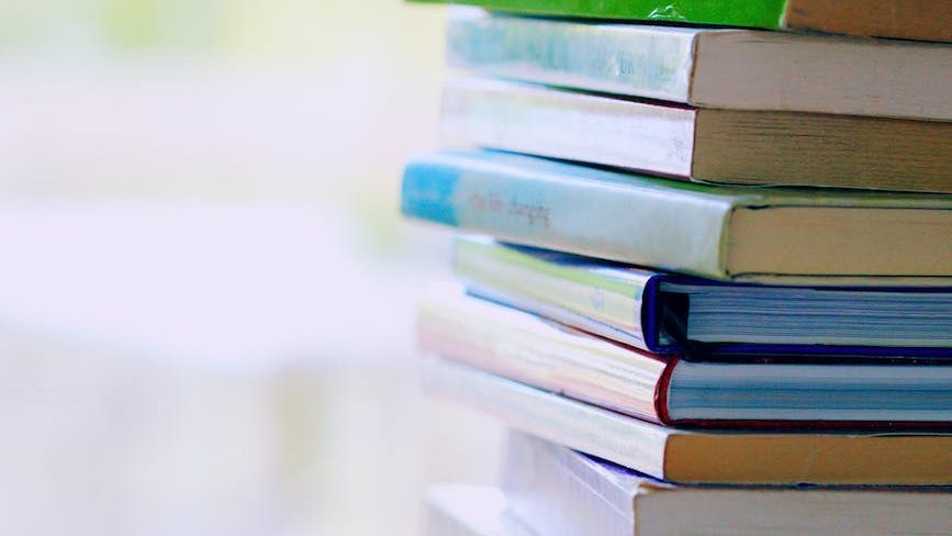 Self-help resources for Narcissistic abuse recovery - Stack of self-help books on a table representing resources and tools for healing.