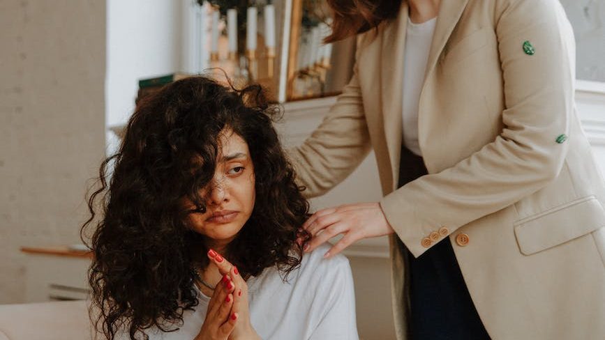 Therapist providing support to a client - Compassionate therapist comforting a client with a supportive hand on the shoulder.