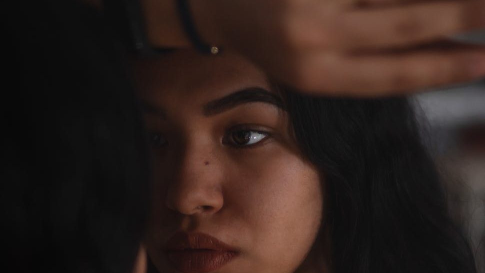 A reflective moment captures the internal struggle of imposter syndrome as a young individual gazes into the mirror, questioning their worth and accomplishments.