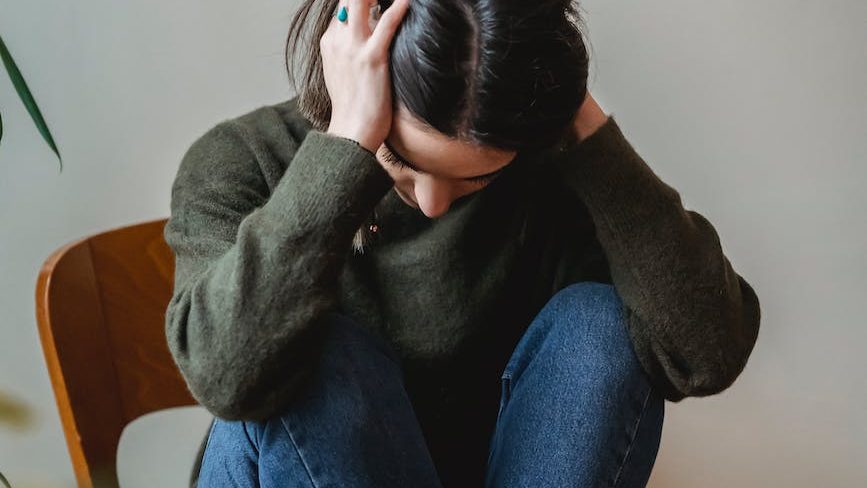 Emotional distress after Narcissistic abuse - Illustration of a person sitting alone in a dark room with a sad expression.