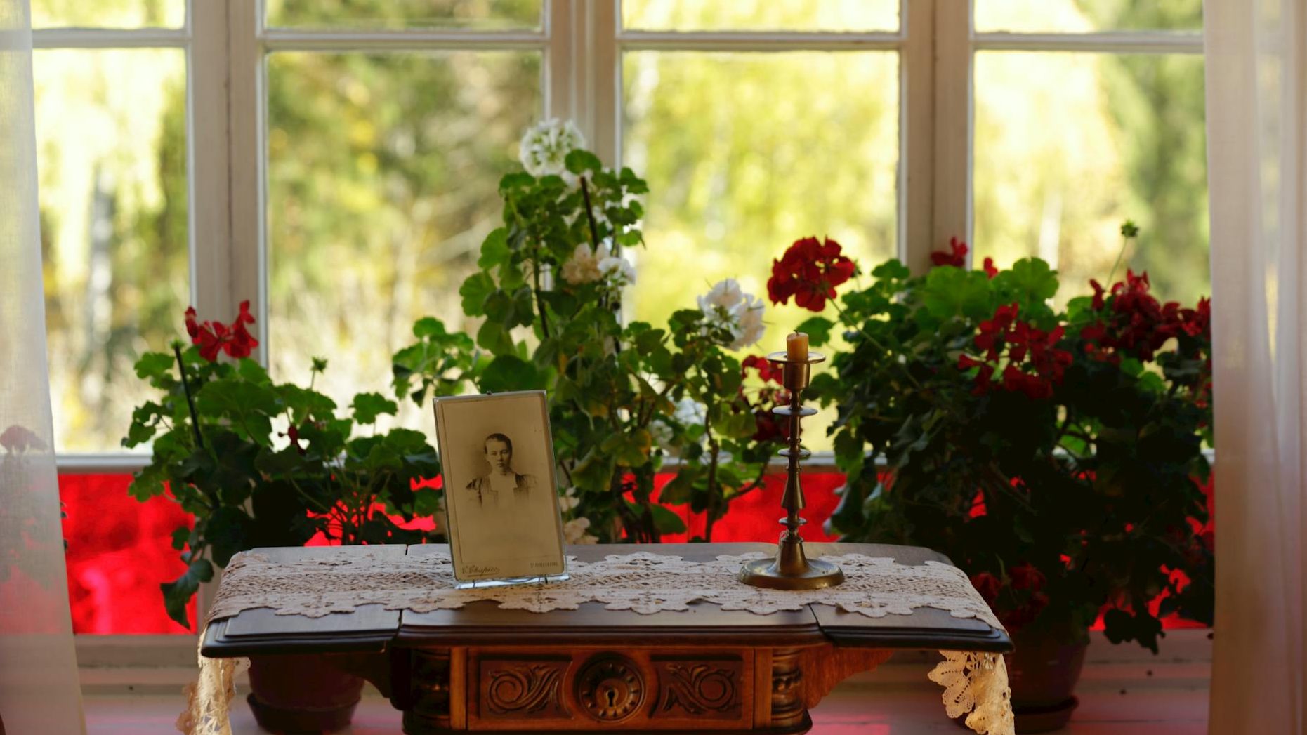 A lit candle surrounded by flowers, symbolizing remembrance and honoring the memory of a loved one.