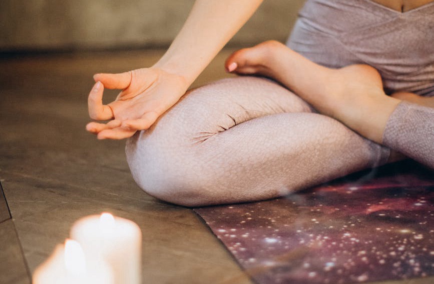 Person sitting in meditation pose with eyes closed and hands resting on knees, symbolizing mindfulness practice.