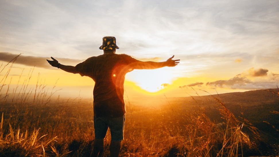 A person standing on a mountaintop, arms outstretched, symbolizing the courage and liberation that comes from embracing vulnerability and authenticity.