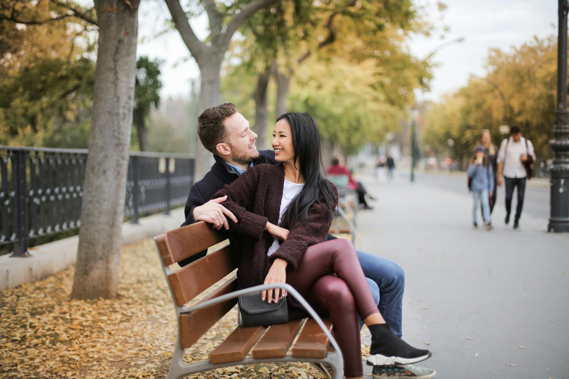A happy couple sitting on a park bench, holding hands and smiling, illustrating the importance of connection and support in overcoming anxiety in relationships.