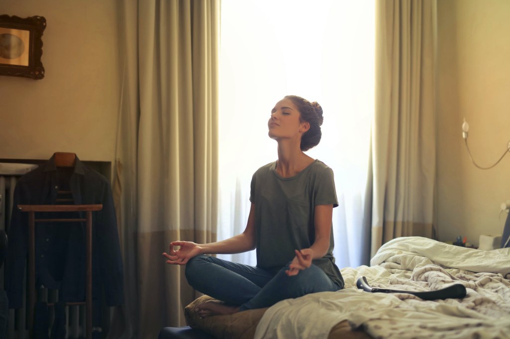 Person sitting in meditation with sunlight streaming through the window.