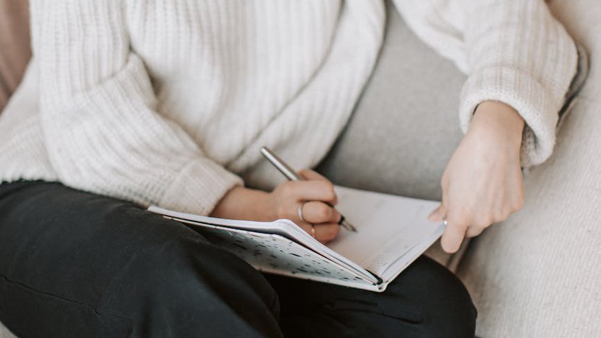 A person journaling in a cozy space, finding solace and comfort in self-expression. Jennifer Adair, LPC, Onesta Therapy Co.