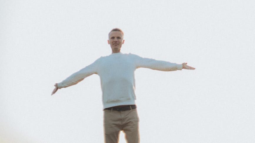 Person standing in serene natural setting with arms outstretched toward sky, symbolizing mental clarity and peace.