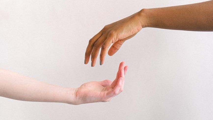 Two hands reaching out to each other, one offering support and comfort to the other, symbolizing the importance of empathy, understanding, and connection in fostering resilience in relationships.