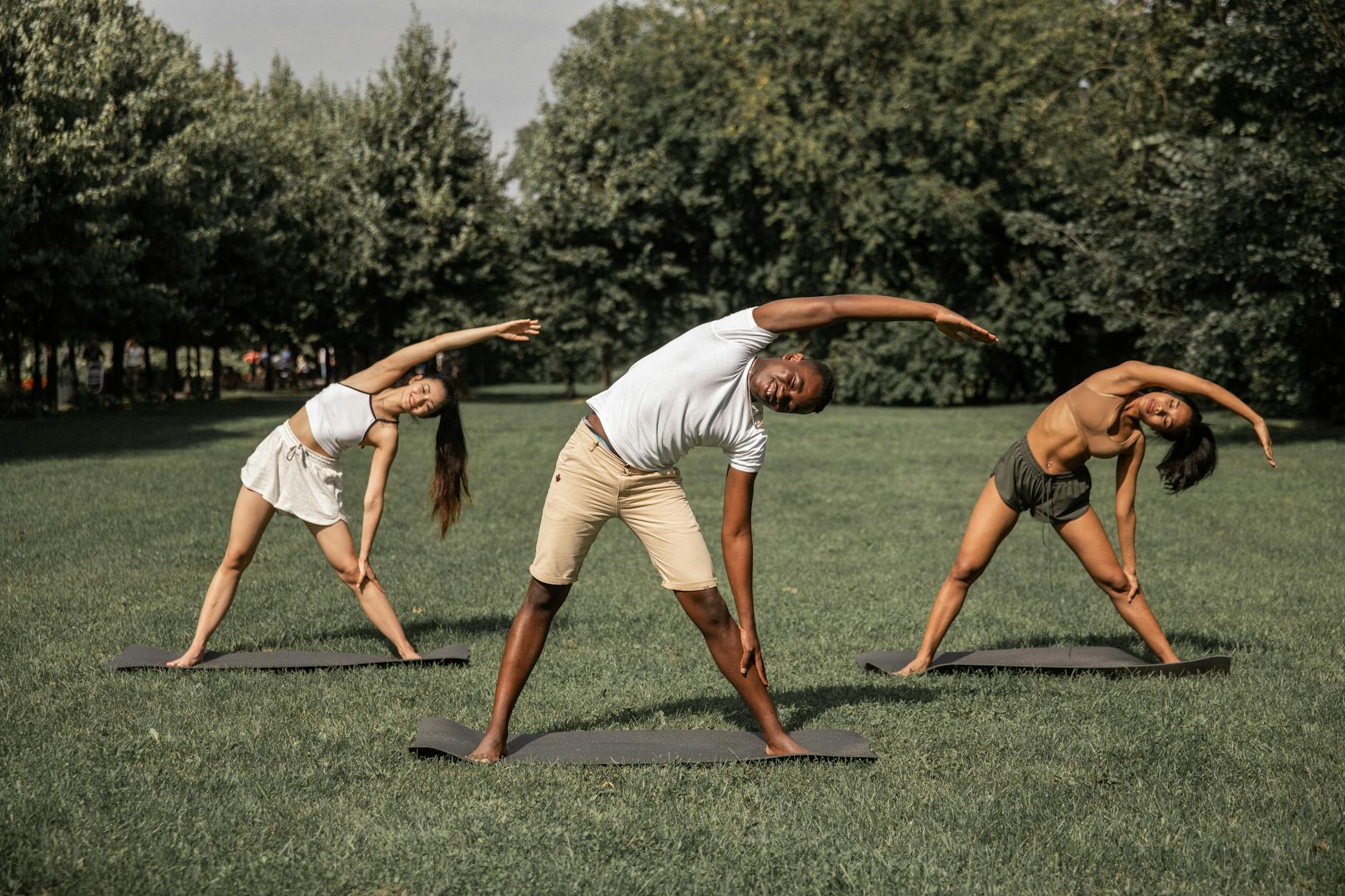 A group of individuals of various ages and backgrounds practicing yoga in a serene outdoor setting, highlighting the benefits of exercise and movement for chronic pain management.