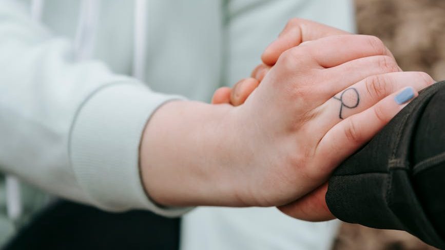 Person reaching out for support from friend, hands clasped with expression of vulnerability and trust.