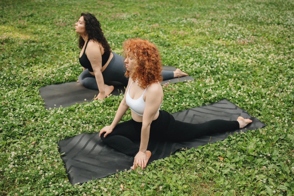 Person practicing yoga outdoors in a green park surrounded by trees