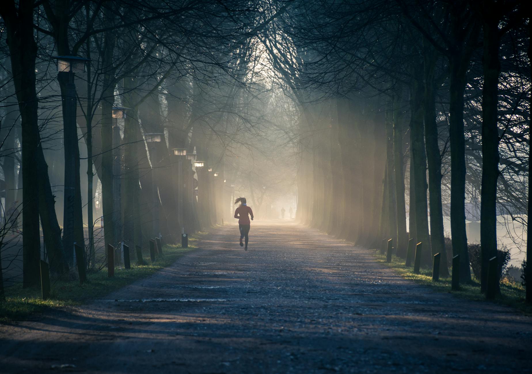 A person engaging in physical activity, jogging outdoors with a smile on their face, demonstrating the stress-relieving benefits of exercise for mental health.